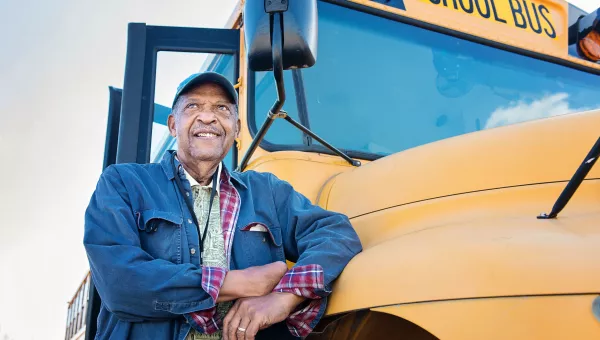 Man standing next to school bus talking about heart and vacular care