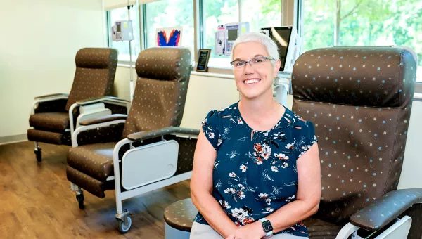 Patient Kristen Keen sitting in a chair and smiling at camera in the chemotherapy room