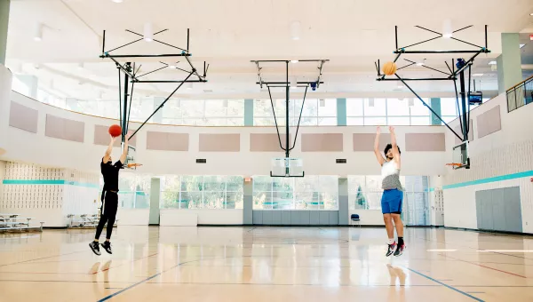 two people shooting a basketball into a basketball hoop