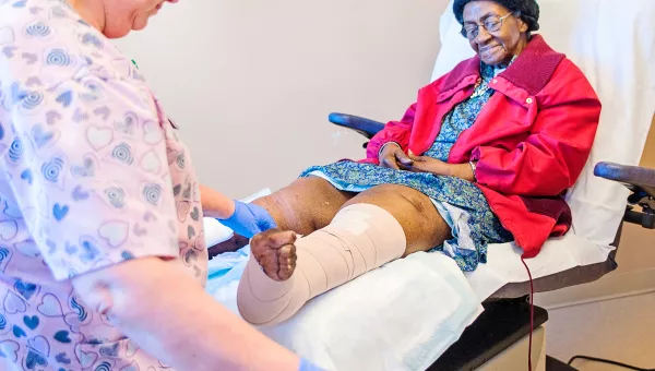 care team member helping patient wrap a leg wound