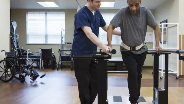 Physical therapist helping patient walk