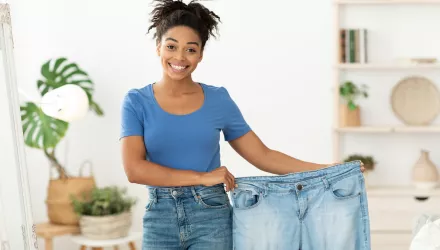 Woman holding large pants to show off weight loss