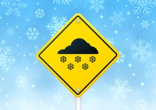 A graphic of a road sign for snow. A yellow sign with a black icon of a snowing cloud.